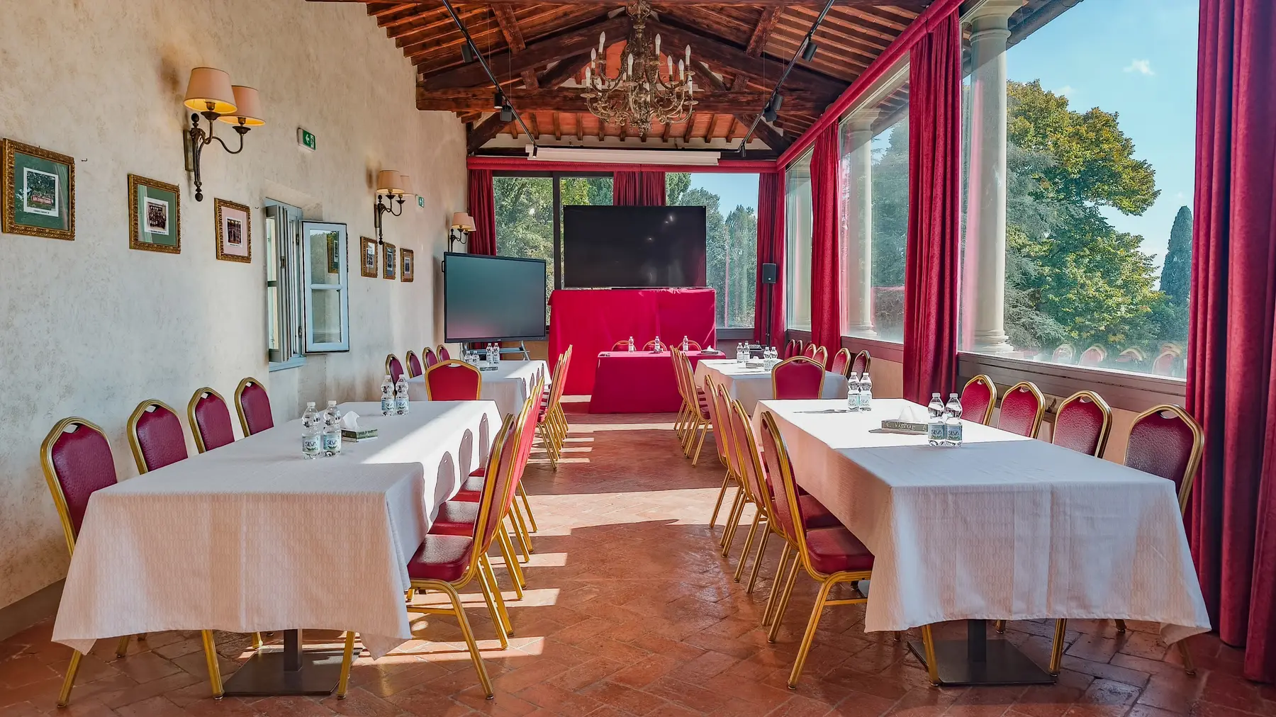 La sala meeting del Fantastic Garden allestita per un corso: tavoli disposti a ferro di cavallo, sedie rosse, due schermi e le finestre che danno sul parco.